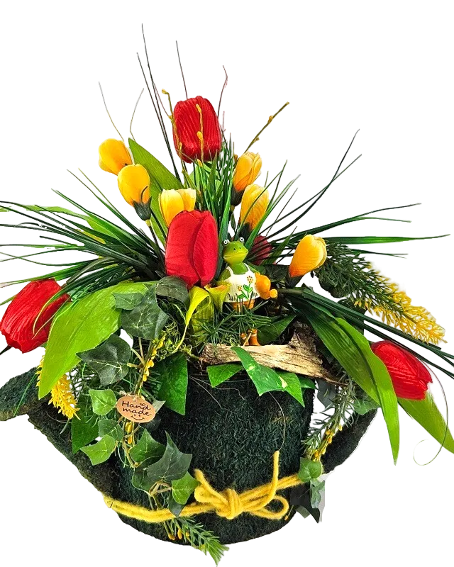 Mit Moos besetzte Gießkanne in der Öffnung ein künstliches Gesteck mit Krokusse und Tulpen aus der Blütenpracht guckt ein witziger Frosch hervor